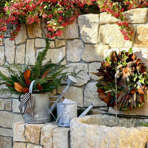 Fountain with magnolia wreath and vintage watering cans