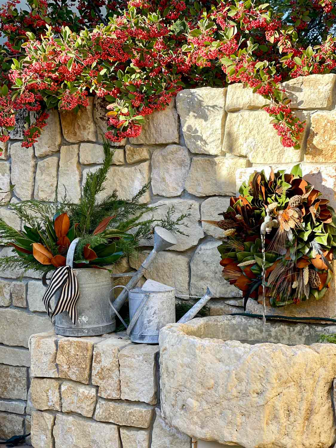 Fountain with magnolia wreath and vintage watering cans