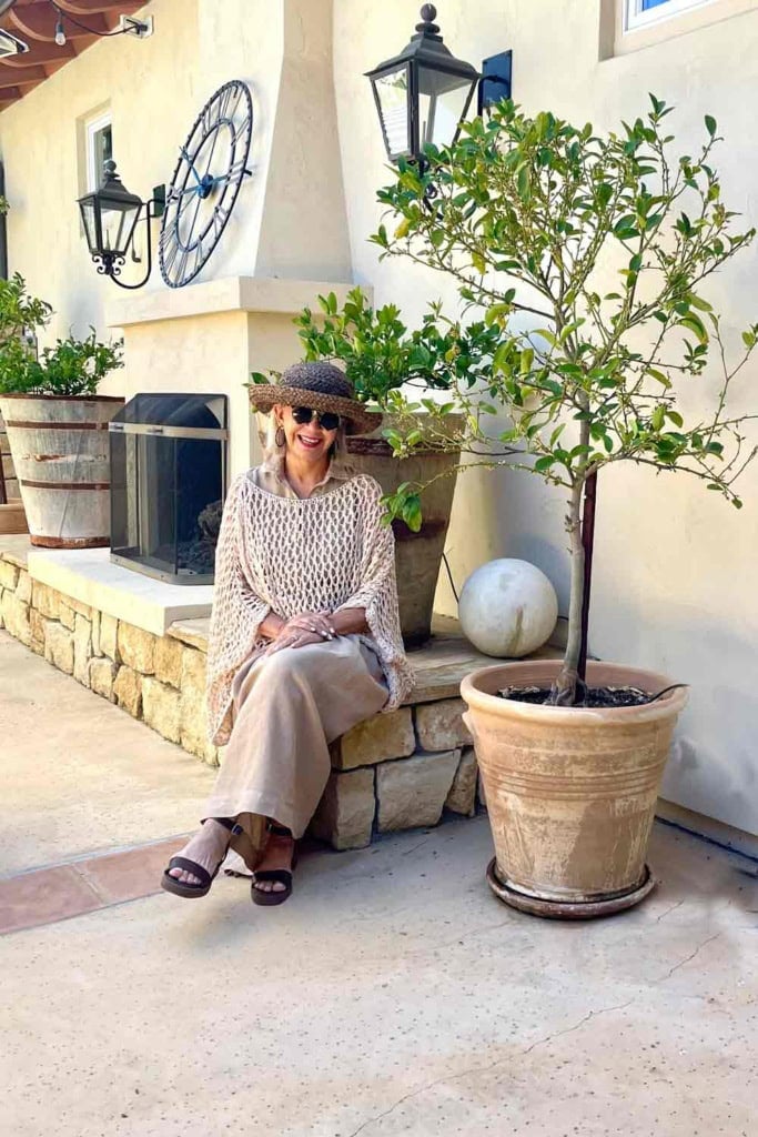 khaki midi dress with open weave sweater, brown hat and sandals
