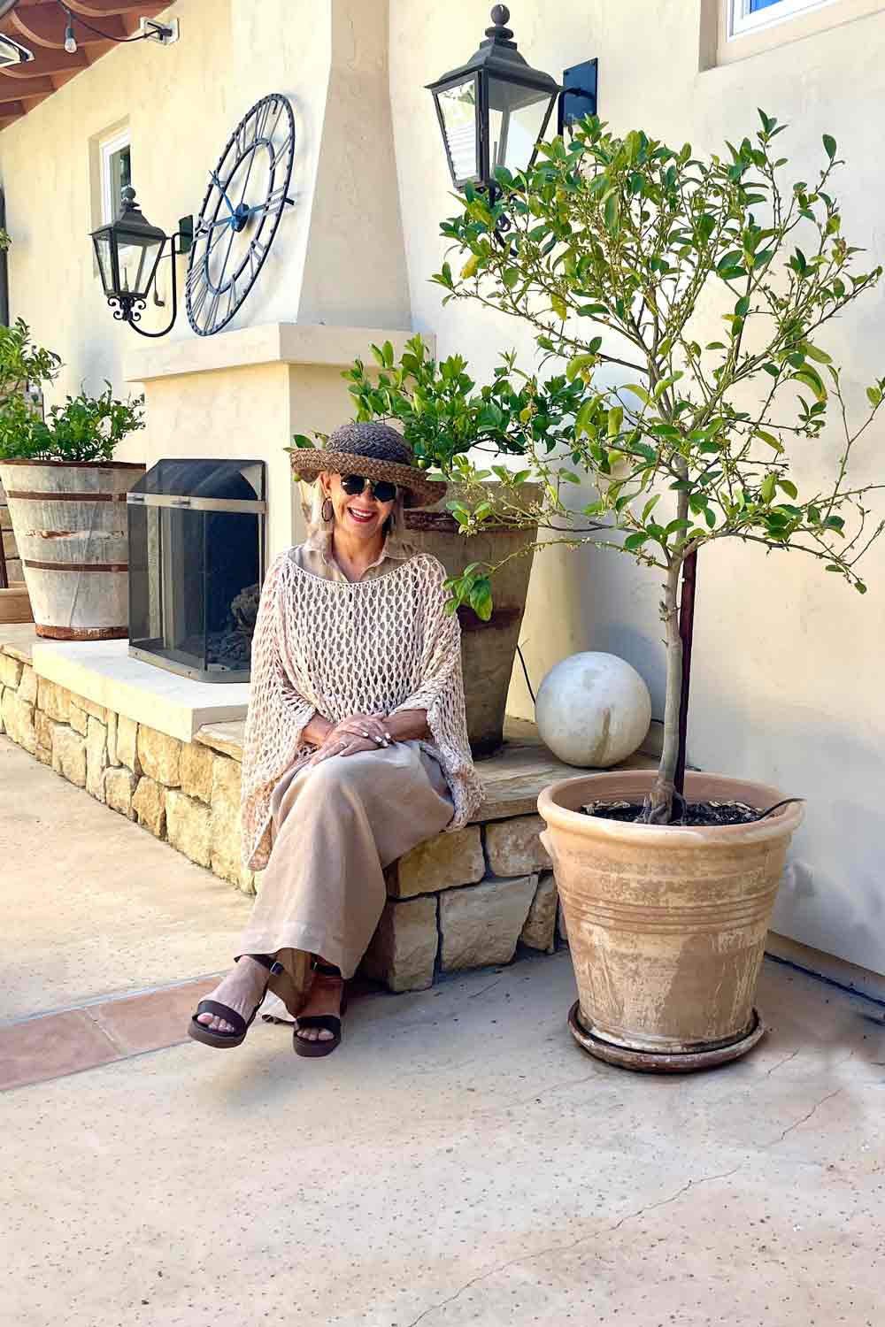 khaki midi dress with open weave sweater, brown hat and sandals